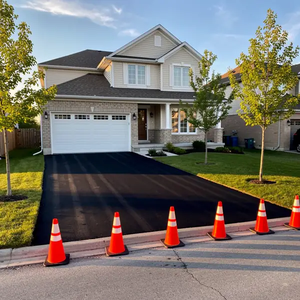 Freshly rolled driveway curing beside garage
