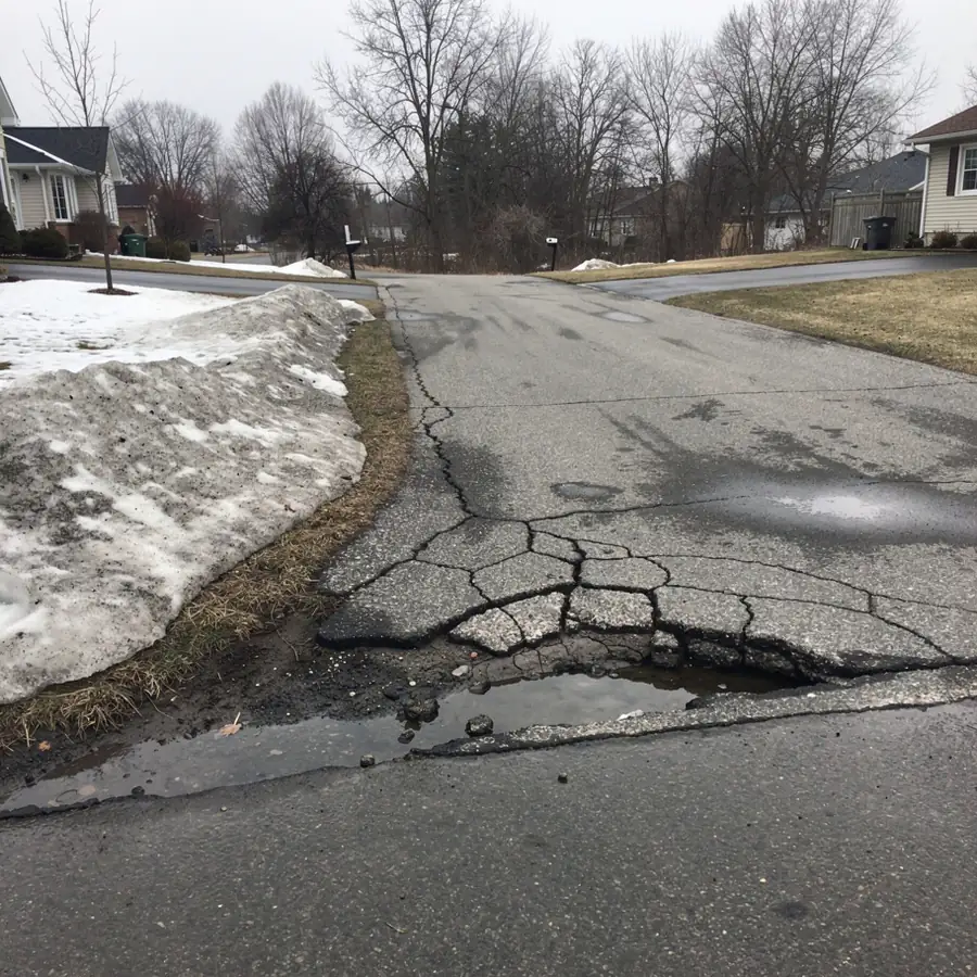 Frost heaved cracked asphalt in early spring